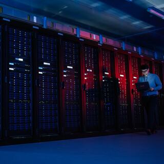 Two IEM employee walking through a data center holding a laptop with the IEM logo