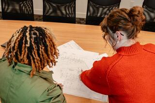 Two IEM employees collaborating over engineering drawings in an office