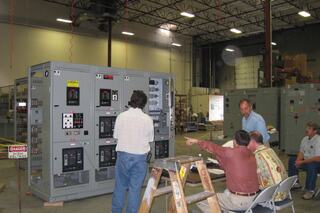 A photo from IEM's archives: 80's Testing featuring a group of employees pointing at a product